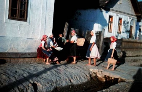 H�z el�tti kispadon �l� aszonnyok. H�rman most �rkeznek kosarakkal a kez�kben. A ruh�zatuk sz�nes, de egyszer�, szokny�t, fejkend�t viselnek.