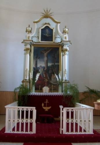 F�olt�r, a megfesz�tett J�zust �br�zol� festm�nnyel. A festm�ny k�r�l feh�r sz�n�, arany mint�zattal d�sz�tett faragv�nyokkal. Az olt�r el�tt b�borv�r�s sz�nyeg l�that�.