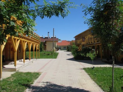 F�b�l k�sz�lt, emeletes �p�letek parkos�tott k�rnyezetben. A k�p k�zep�n �t halad, a h�tt�rben k��p�let l�that�.