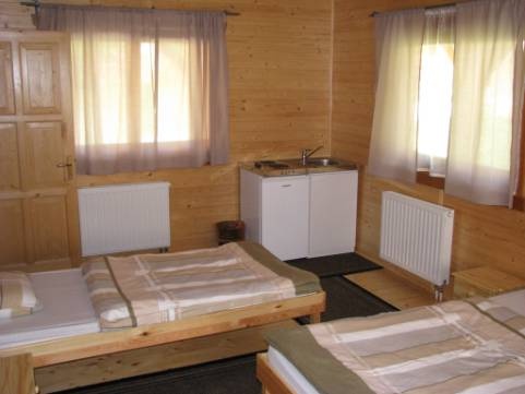 Nat�r sz�n� lamb�ri�val bor�tott szobabels�. Az ablakokon feh�r f�gg�ny. A k�pen 2 �gy l�that�. Rajtuk �sszehajtogatott �gynem�vel. A sarokban egy feh�r mosogat�szekr�ny l�that�.